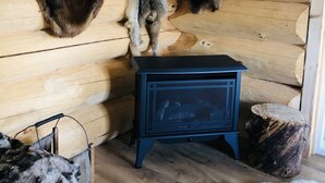 A log cabin interior with fur pelts hanging on the wall, a blue heater, and a rustic wooden floor. - Wrangell Mountain Lodge (Chitina)