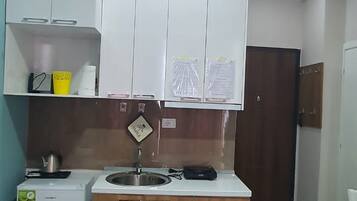 A compact kitchen with a refrigerator, sink, and wooden cabinets.