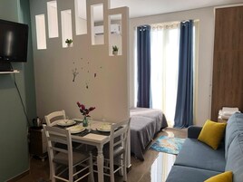 A compact living space with a dining area, a bed, and a sofa.