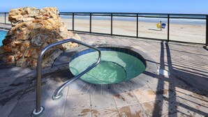 A stone wall, a metal pool ladder, and a beach view. - One Bedroom Condo, Ormond Beach 1851342 (Ormond Beach)