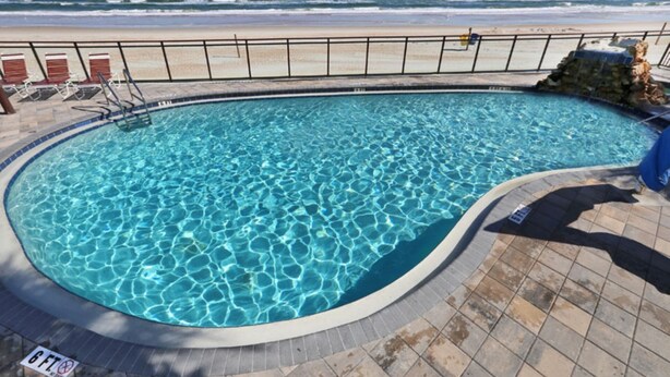 A swimming pool with a view of the ocean. - One Bedroom Condo, Ormond Beach 1851342 (Ormond Beach)
