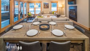 A dining area with a wooden table set for six, a sofa, and a fireplace. - 3BR Big Sky Townhome | Walk to Town Center, Hot Tub & Sleeps 12 (Big Sky)