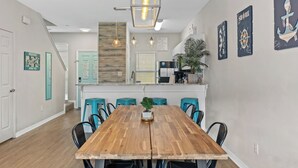 Eine moderne Küche mit einer Holzinsel, Türkis-blauen Barhocker und einer hängenden Leuchte.