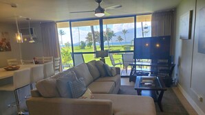 Ein Wohnzimmer mit Sofa, Fernseher und Essbereich mit Blick auf einen Golfplatz.