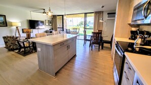 Een moderne keuken met een centraal eiland, houten vloeren en een eethoek met stoelen en een tafel.