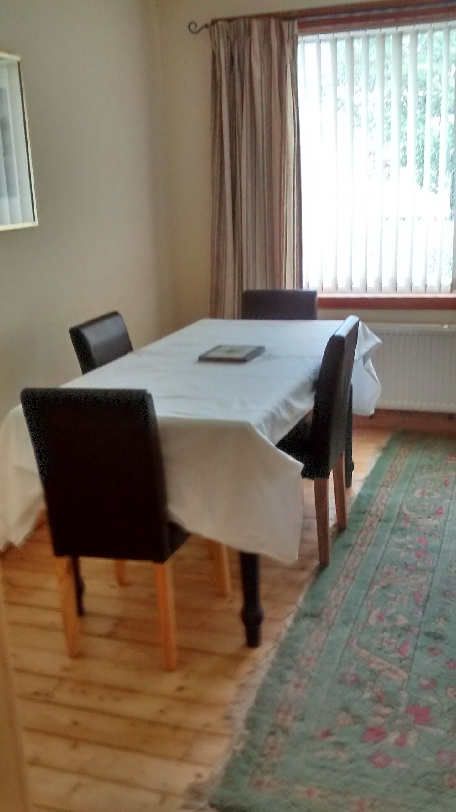 Un coin repas comprenant une table, des chaises, un tapis et une fenêtre avec des rideaux.