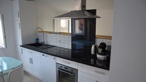 A modern kitchen with white cabinets, a black countertop, a stainless steel range hood, a dishwasher, and a built-in oven. - The edge of Saint Quentin 10 minutes from METZ at the foot of Mont Saint Quentin (Lessy)
