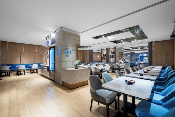 A modern restaurant with a central counter, multiple seating areas, and a clean, contemporary design.