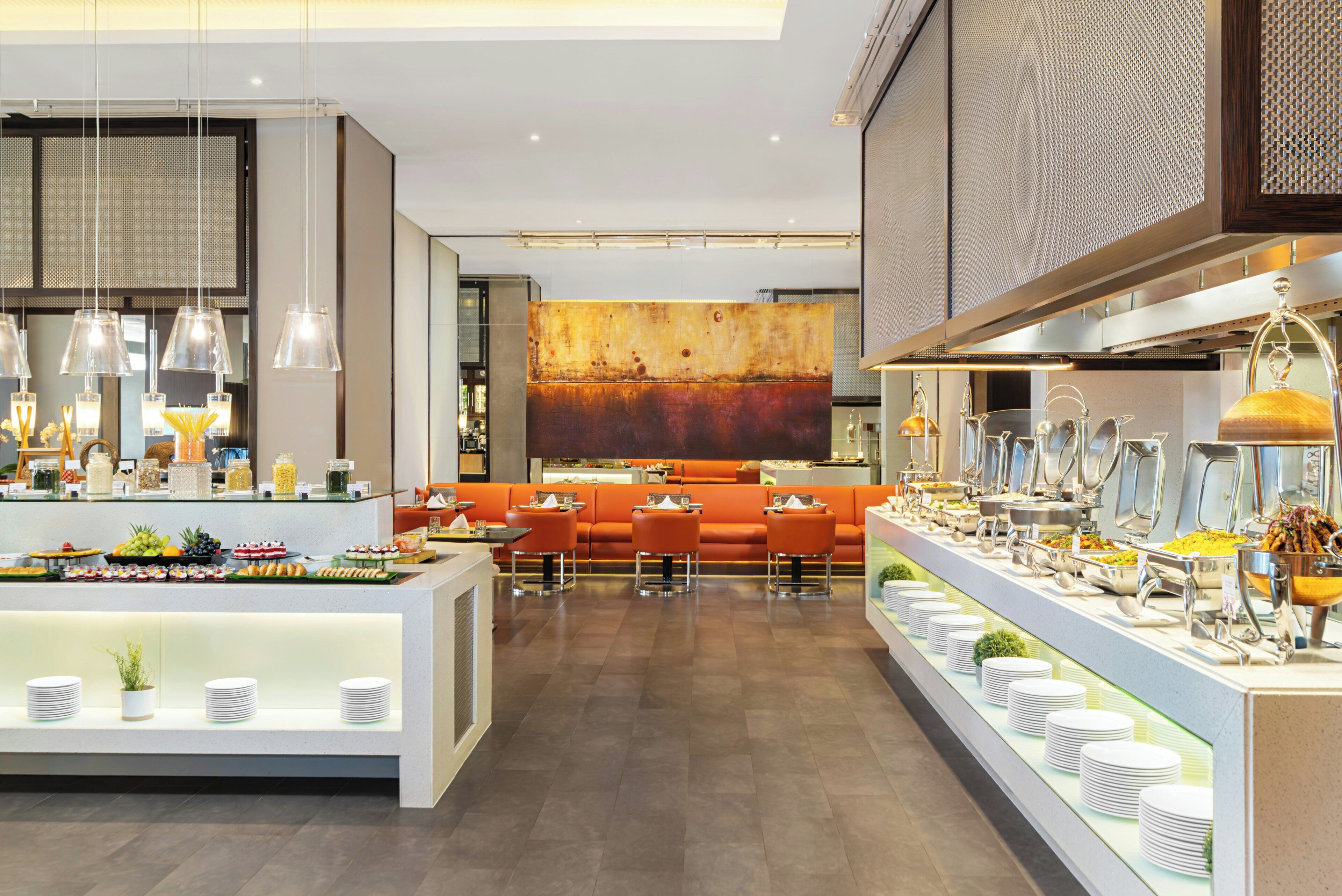 A modern hotel lobby with a buffet area, seating, and a large abstract painting on the wall.