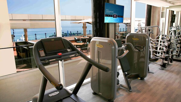 A gym with cardio equipment, weight machines, and a TV screen displaying a welcome message. - Centro Corniche Al Khobar (Al Khobar)