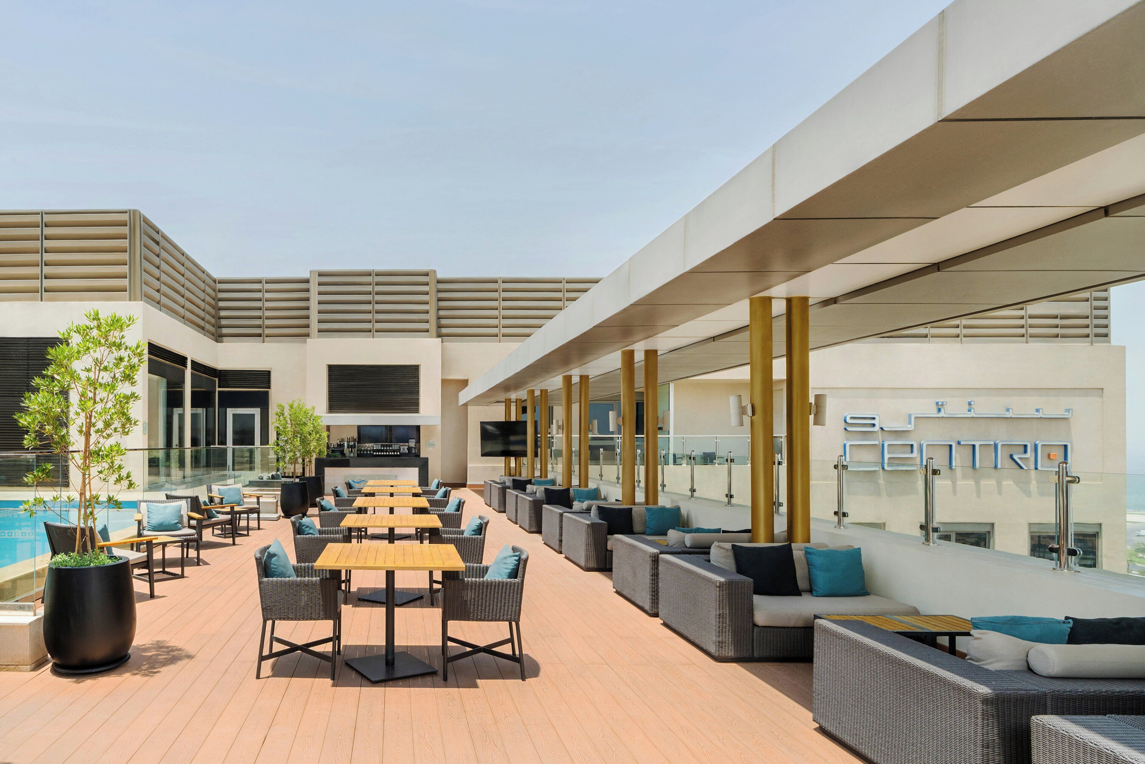 A rooftop lounge with outdoor seating, a pool, and a modern architectural design.