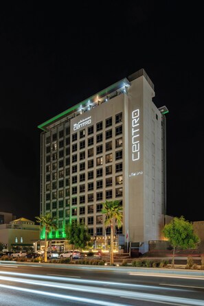 Un hotel de varios pisos con un llamativo letrero que dice 'CENTRO', con un diseño arquitectónico moderno que incluye un techo plano y una serie de ventanas.