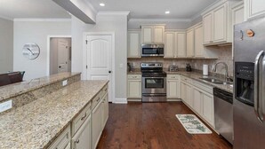Una cocina moderna con encimeras de granito, electrodomésticos de acero inoxidable y armarios de colores claros.