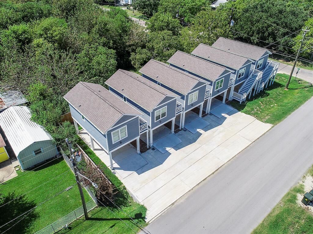 Une rangée de maisons de ville à trois étages, avec une allée centrale et un petit jardin à l’avant.