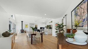 Un vaste espace de vie comprenant une table à manger en bois, des chaises, une cheminée et une grande fenêtre.