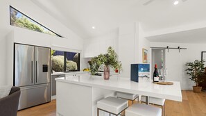 Una cocina moderna con una isla grande, electrodomésticos de acero inoxidable y vistas al exterior.