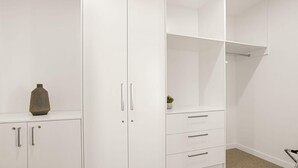 Une armoire blanche avec de nombreux tiroirs et des portes, un petit vase sur la gauche et une plante sur la droite.