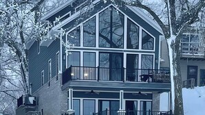 Una casa de dos pisos con balcón, ventanas amplias y garaje.