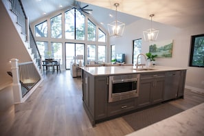 A modern kitchen with a large island, stainless steel appliances, and a dining area with a view.