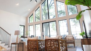 Una habitación amplia con techo alto, ventanas grandes y una lámpara moderna.