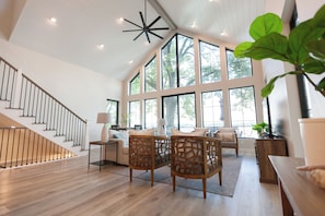 A spacious living area with a wooden staircase, large windows, and a modern ceiling light fixture. - Custom lake home, dock/boat lift, private beach, sleeps up to 15 see description (Ventura)