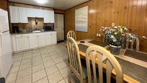 Une cuisine avec des meubles blancs, un four à micro-ondes et une table à manger avec des chaises.