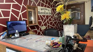 A reception desk at the Ranchland Inn with a computer monitor, a clock, and a welcome sign.