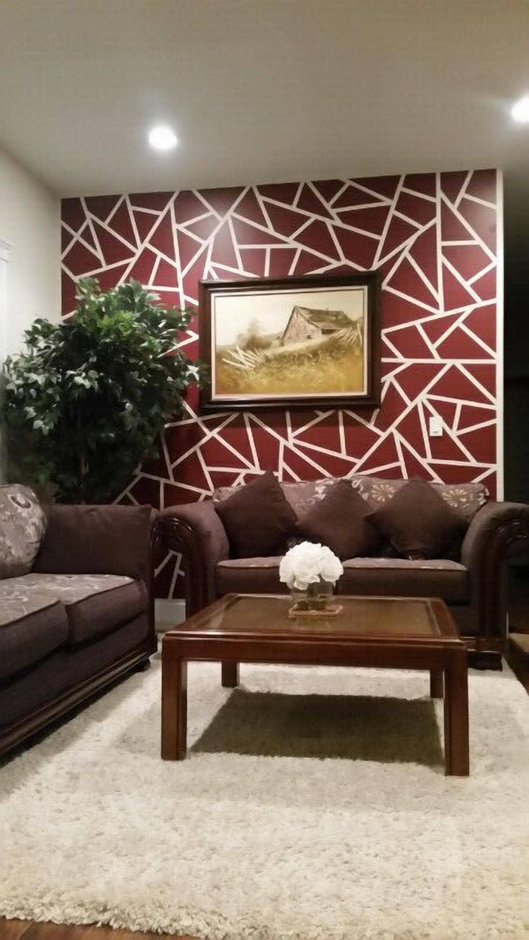 A living room with a patterned wall, a sofa, a coffee table, and a large plant.