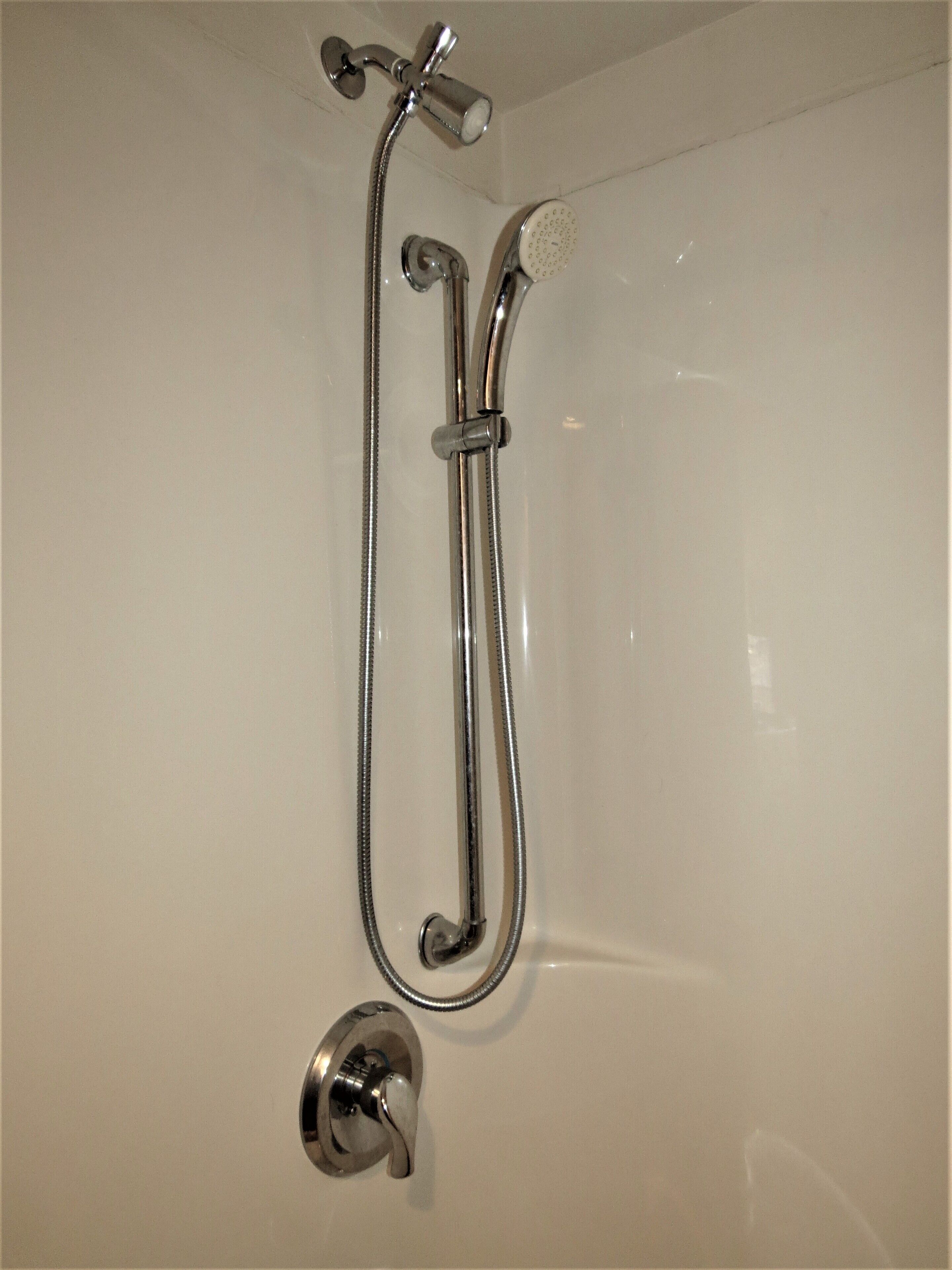 Baño con sistema de ducha, que incluye un cabezal de ducha de mano y uno fijo.