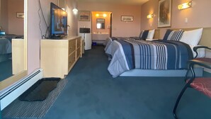 A hotel room with a bed, a desk, a chair, a dresser, and a mirror. - Ranchland Inn (Nanton)