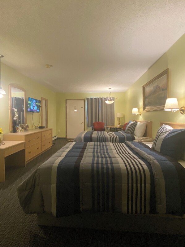 A hotel room with a bed, a desk, a television, and a painting on the wall.