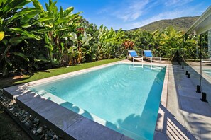 Relax by the serene pool surrounded by lush vegetation and mountain views.