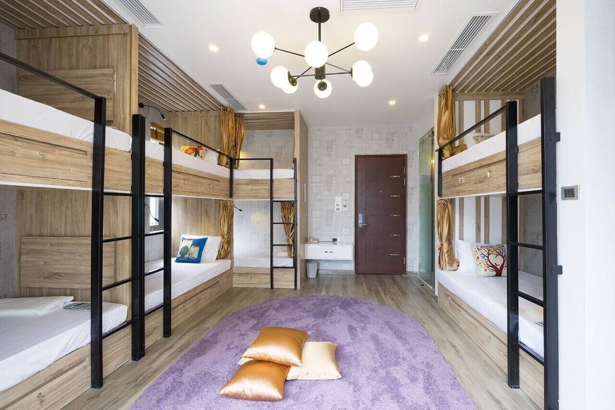 A room with bunk beds, a bathroom, and a purple rug.