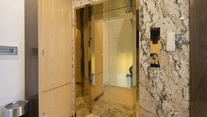 A hotel room with a marble floor, a wooden door, and a mirror reflecting the room. - BBQ Hostel Ha Long (Ha Long)