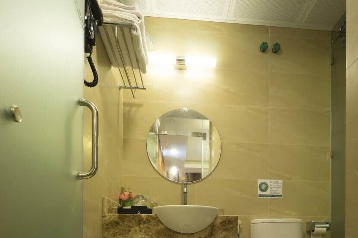 A small bathroom with a sink, mirror, toilet, and a shower area.