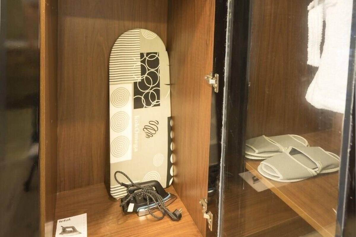 A wooden cabinet with a safe, a vintage telephone, and a surfboard with a design.