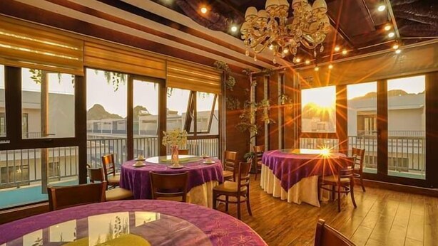 A restaurant with round tables, purple tablecloths, and a chandelier. - BBQ Hostel Ha Long (Ha Long)
