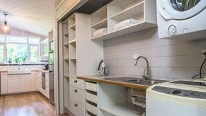 Un cuarto de lavandería con lavadora, pileta y estantes de almacenamiento.