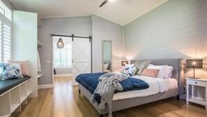 Un dormitorio con cama, una banca, un espejo y una lámpara colgante.