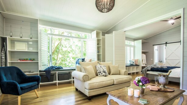 Una sala de estar con sofá, sillón, mesa de centro de madera y estantería.