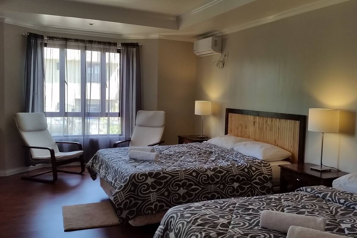 Habitación de hotel con dos camas, una silla, un escritorio y una ventana con cortinas.