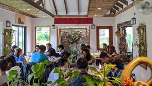 Un restaurant avec des poutres en bois, une enseigne indiquant « Joyeuses fêtes » et des plantes d’intérieur.