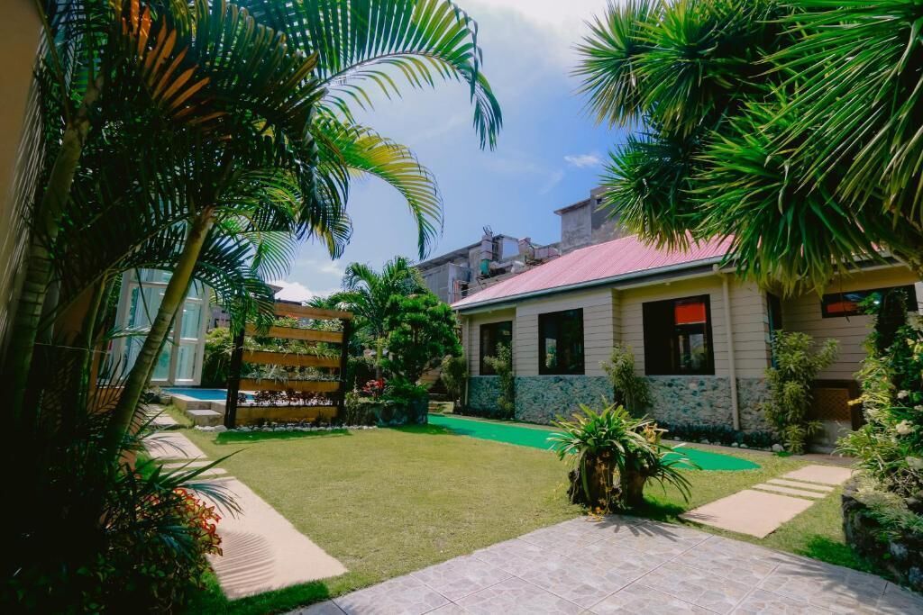 Una propiedad residencial con césped cuidado, piscina y una variedad de plantas tropicales.