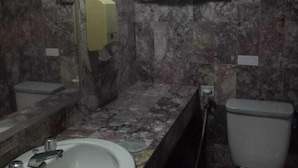 A bathroom with a marble sink, a toilet, and a towel rack. - Rauda Hotel Syariah (Pekanbaru)