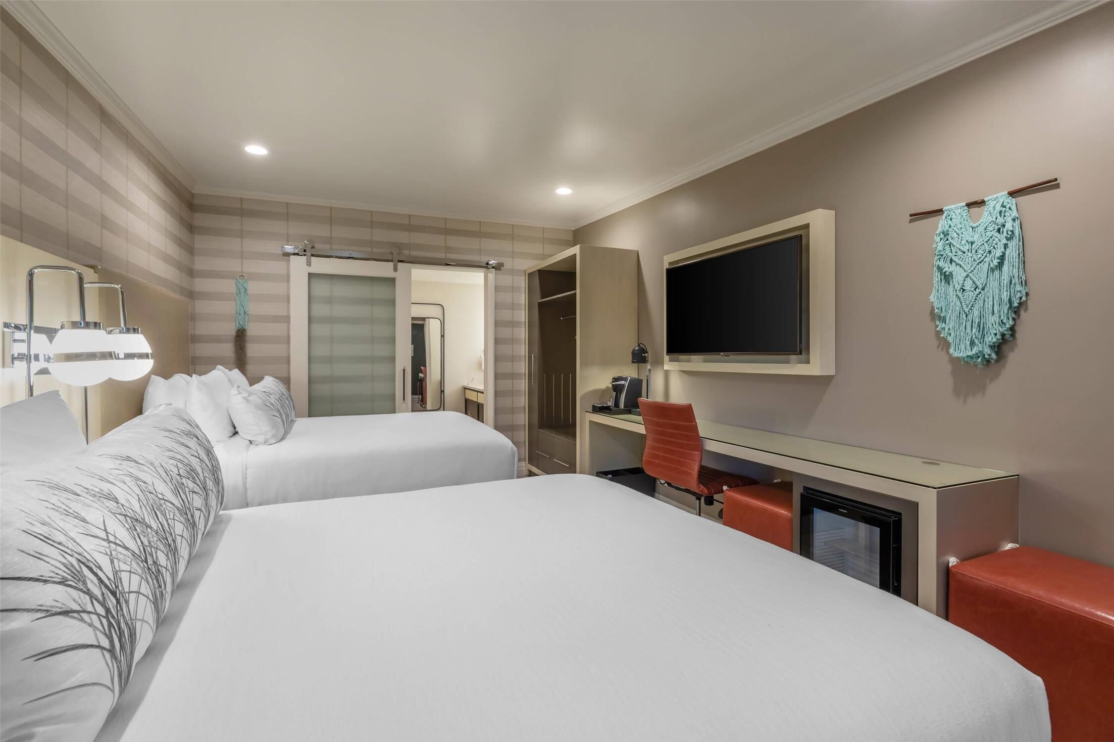 A hotel room with two beds, a desk, a chair, a television, and a wardrobe.