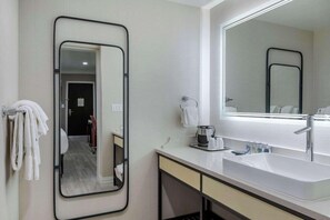 Une salle de bain moderne avec un grand miroir, un lavabo et un porte-serviettes.