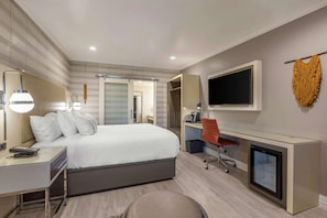 Relax in a clean and functional room with a comfortable bed, desk area, and TV.