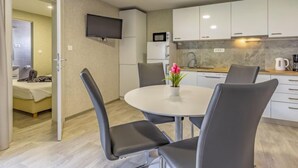 Et lille hotelværelse med spiseplads, tekøkken og et fjernsyn hængt på væggen.
