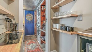 A kitchen with a built-in stove, wooden shelves with glassware, and a blue accent wall. - The View Finder at Tannery Flats - Newly Renovated! (Johnson City)