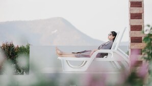 Une personne se détend sur une chaise longue blanche, avec une vue sur les montagnes en arrière-plan.